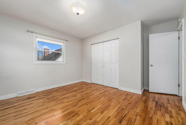 unfurnished bedroom with visible vents, baseboards, a closet, and light wood finished floors