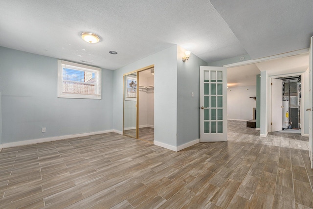 spare room with baseboards, a textured ceiling, and wood finished floors