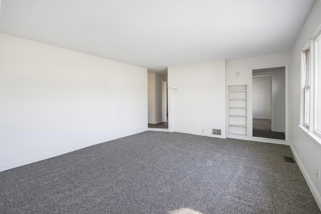 carpeted empty room featuring visible vents, plenty of natural light, and built in shelves