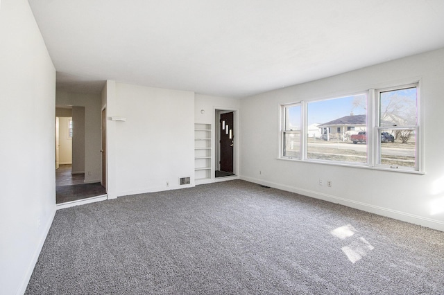 empty room featuring baseboards, visible vents, and carpet floors