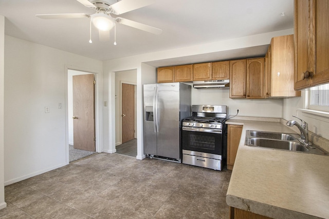 kitchen featuring under cabinet range hood, brown cabinets, stainless steel appliances, a ceiling fan, and a sink