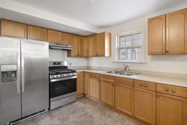 kitchen with brown cabinetry, a sink, stainless steel appliances, light countertops, and under cabinet range hood