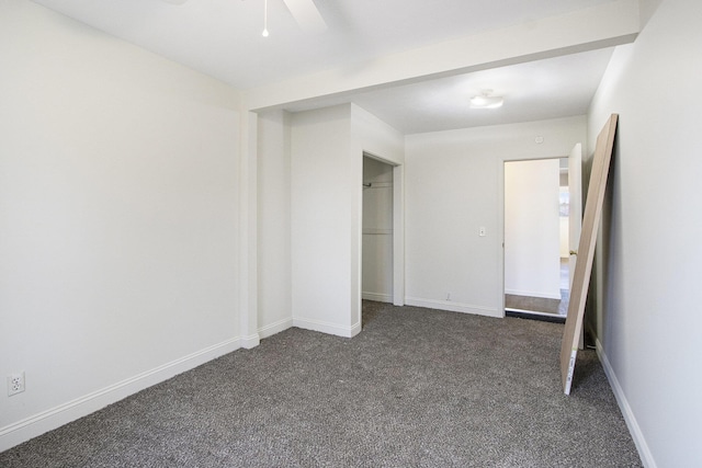 unfurnished bedroom featuring a ceiling fan, baseboards, dark colored carpet, and a closet