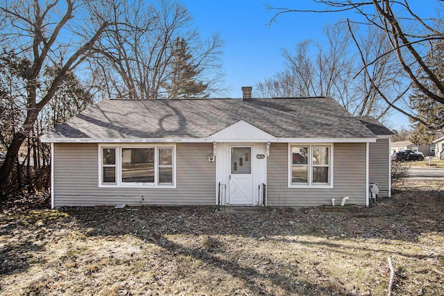 view of front of property with roof with shingles and a chimney