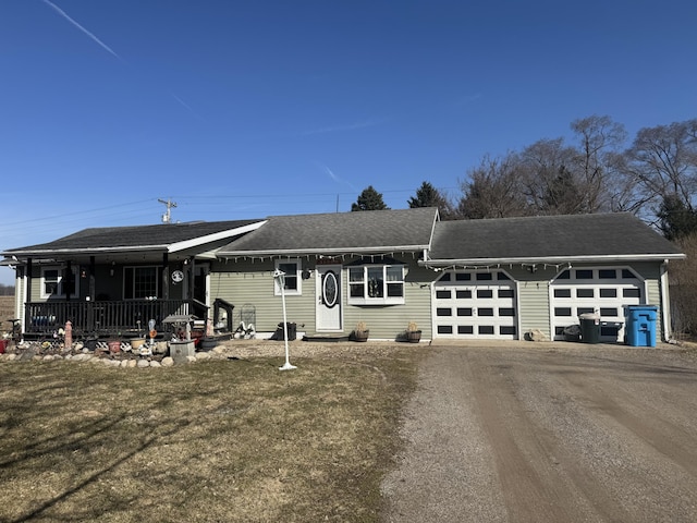 ranch-style home with a shingled roof, dirt driveway, a porch, a front yard, and a garage