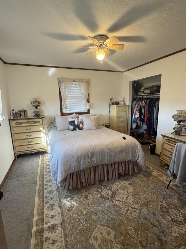 carpeted bedroom with a closet, a textured ceiling, crown molding, and a ceiling fan