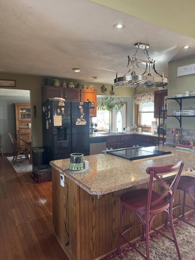 kitchen featuring a kitchen bar, black appliances, dark wood-style floors, recessed lighting, and a peninsula