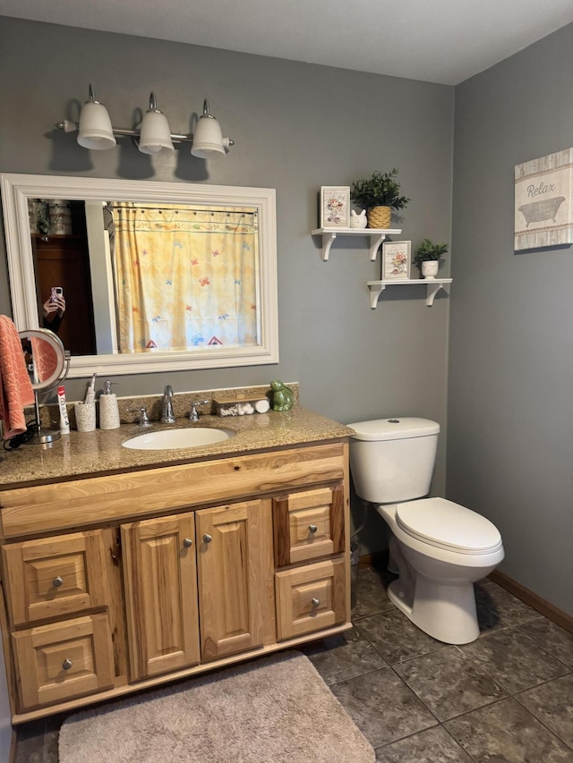 bathroom with vanity, toilet, and baseboards