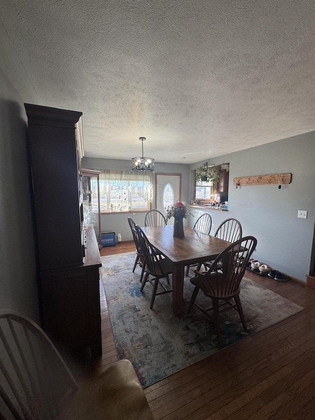 dining space featuring hardwood / wood-style flooring, a notable chandelier, and a textured ceiling