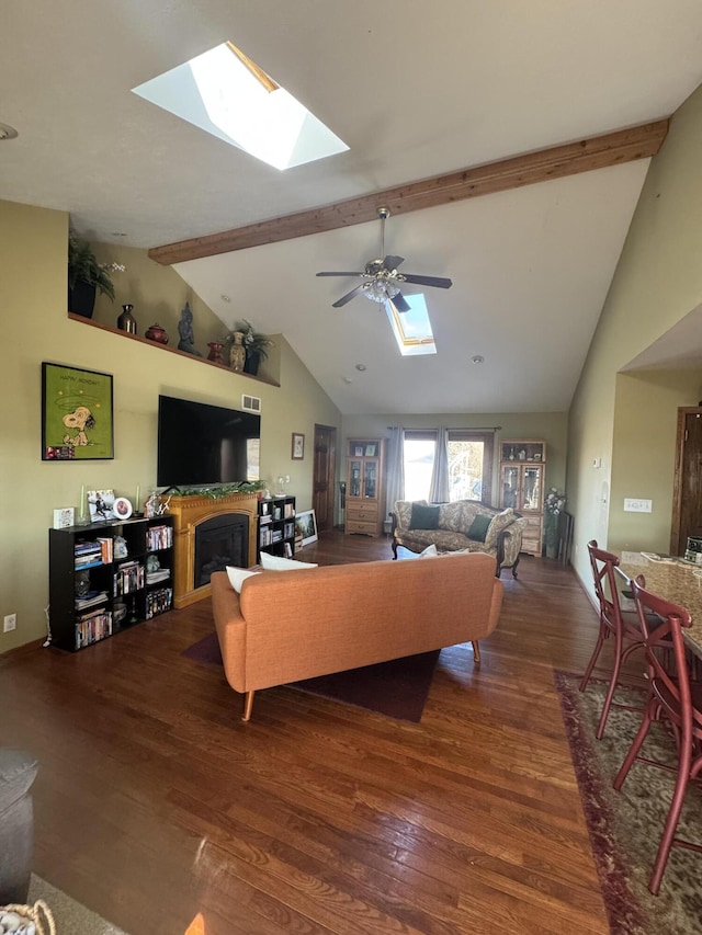 living area with wood finished floors, beam ceiling, a skylight, and a ceiling fan