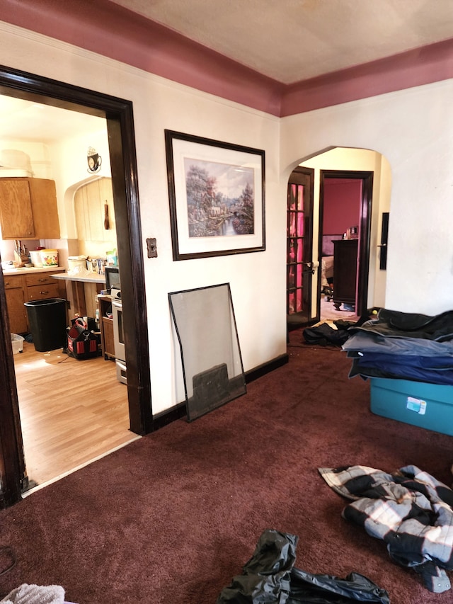 interior space featuring arched walkways, light colored carpet, and baseboards