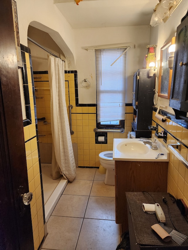 bathroom with toilet, a stall shower, tile walls, tile patterned flooring, and vanity