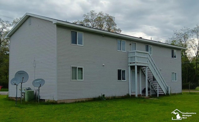 back of property with stairway and a lawn