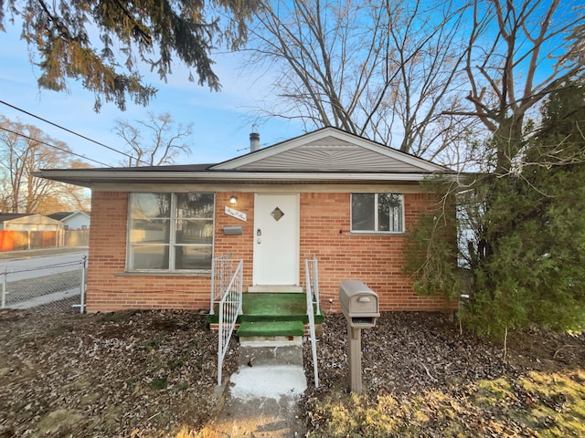 bungalow-style home with fence and brick siding