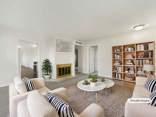 living area with a fireplace with flush hearth, baseboards, and visible vents