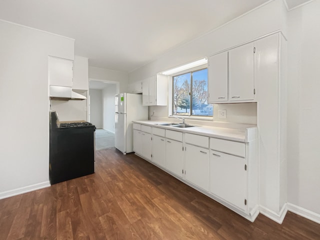 kitchen with gas stove, freestanding refrigerator, a sink, dark wood-type flooring, and light countertops