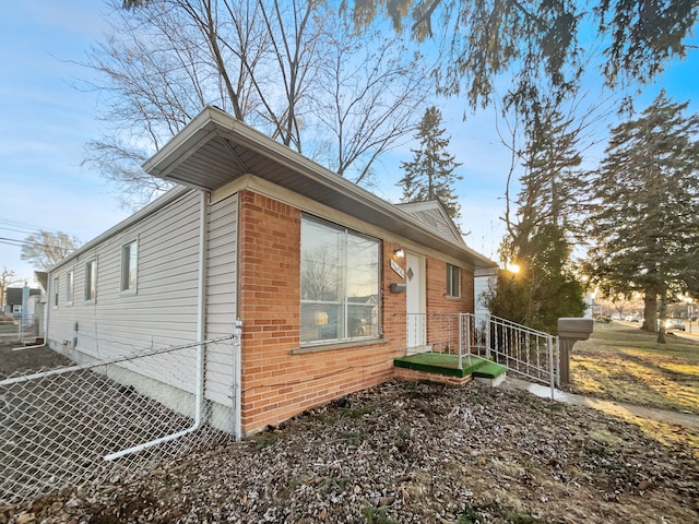 view of side of property featuring brick siding and fence