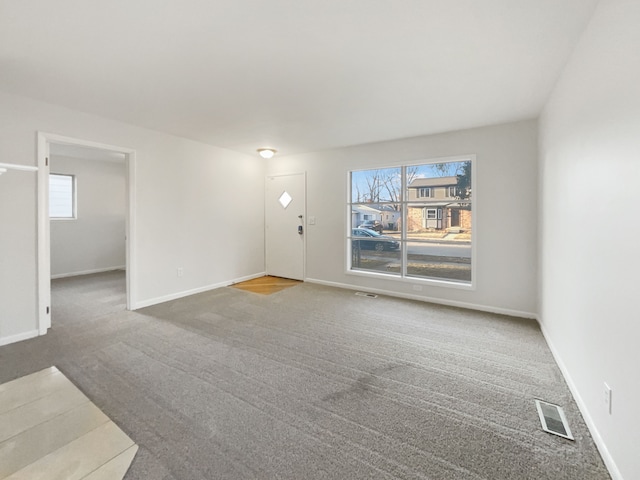 unfurnished living room with carpet flooring, baseboards, and visible vents