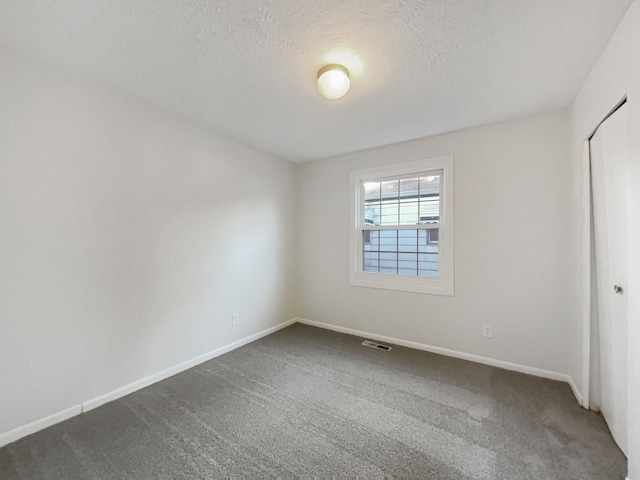 unfurnished bedroom featuring dark colored carpet, visible vents, baseboards, and a closet