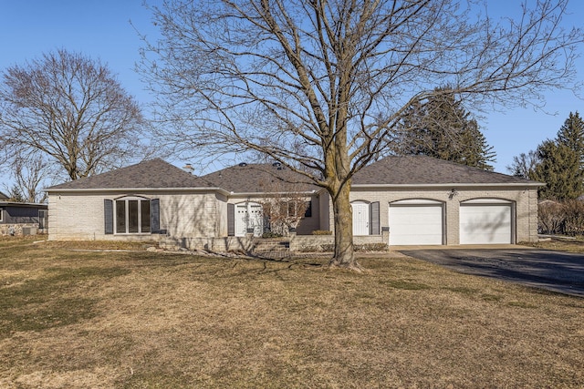 ranch-style home featuring a front yard, driveway, a shingled roof, a garage, and brick siding