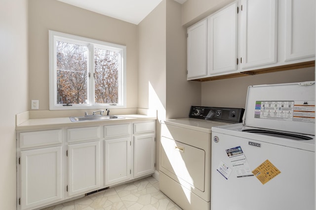 clothes washing area with a sink, visible vents, cabinet space, and independent washer and dryer