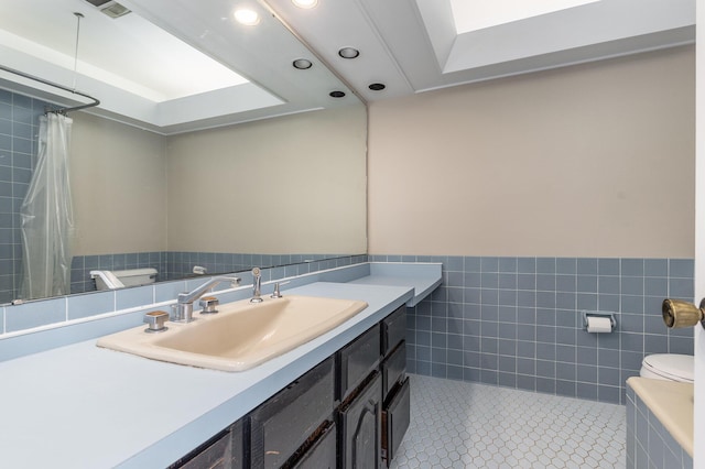 bathroom with tile patterned flooring, tile walls, toilet, and a wainscoted wall