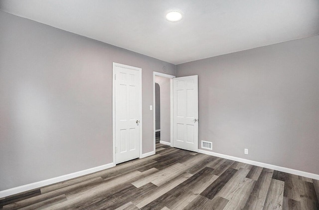 empty room featuring wood finished floors, baseboards, and visible vents