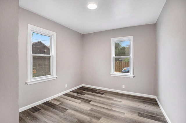 empty room featuring wood finished floors, a healthy amount of sunlight, and baseboards