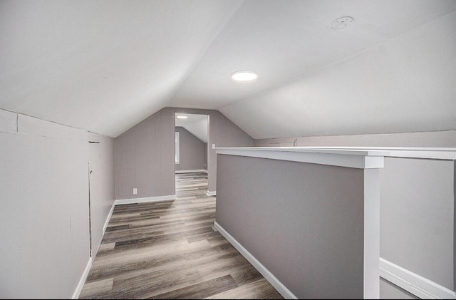 bonus room with lofted ceiling, wood finished floors, and baseboards