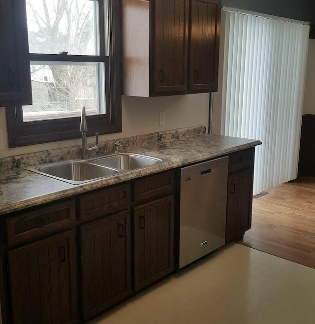 kitchen with light wood finished floors, dark brown cabinets, dishwasher, and a sink