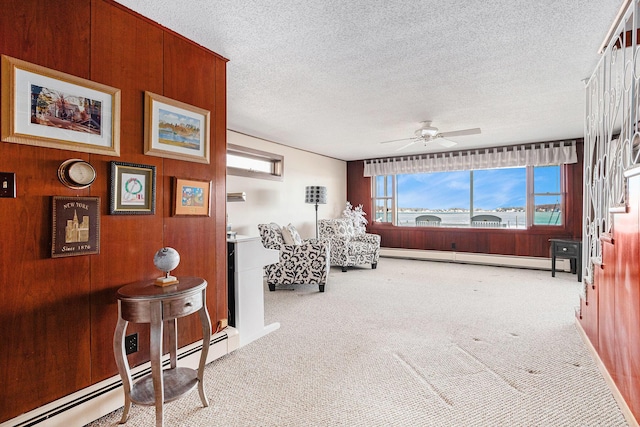 sitting room featuring a baseboard heating unit, carpet, a ceiling fan, and a textured ceiling