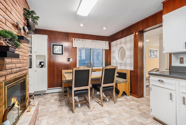 dining area with a textured ceiling, wood walls, and a fireplace