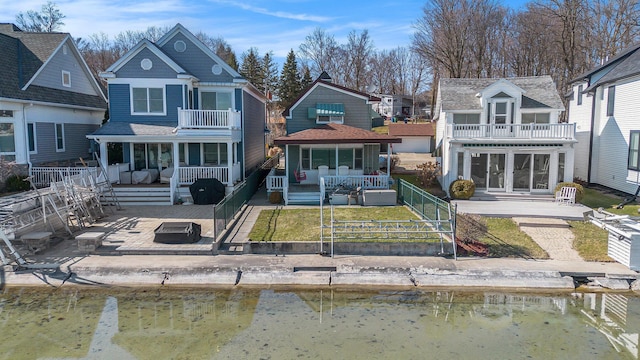 rear view of property with covered porch, a shingled roof, a balcony, fence private yard, and a patio area