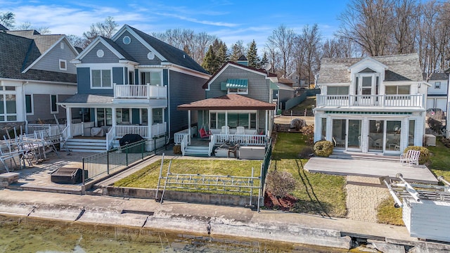 view of front of home featuring a front yard, a balcony, fence, and roof with shingles