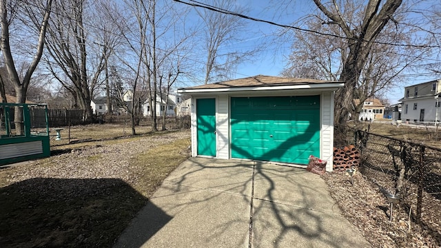 view of outdoor structure featuring an outbuilding, concrete driveway, and fence