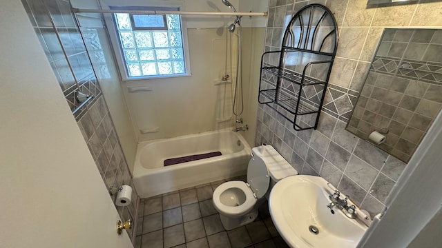 full bath with toilet, shower / bath combination, tile patterned floors, tile walls, and a sink