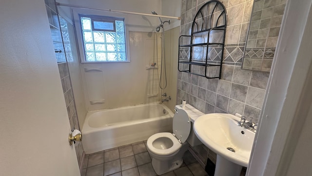 bathroom with tub / shower combination, a sink, tile patterned flooring, tile walls, and toilet