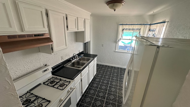 kitchen with under cabinet range hood, a sink, white appliances, baseboards, and a textured wall