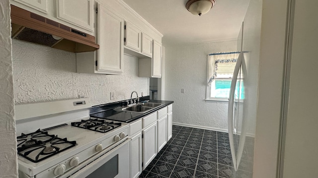 kitchen featuring under cabinet range hood, a sink, baseboards, white range with gas stovetop, and a textured wall