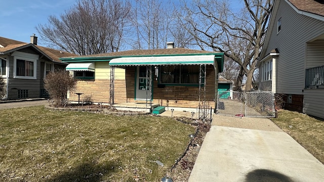 view of front facade with stone siding, a front yard, and a gate