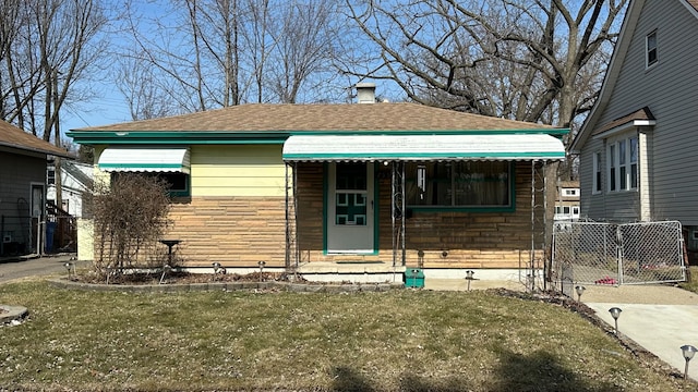 bungalow-style home with stone siding and a front lawn