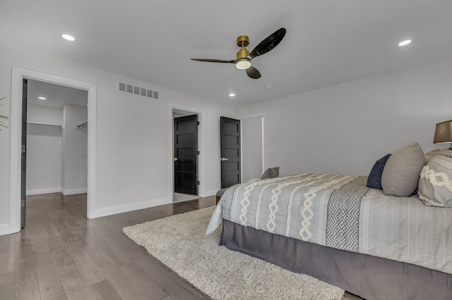 bedroom featuring wood finished floors, visible vents, baseboards, recessed lighting, and a spacious closet