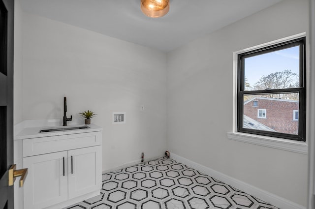 clothes washing area with light floors, baseboards, cabinet space, a sink, and washer hookup