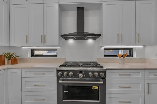 kitchen featuring white cabinets, wall chimney exhaust hood, and gas range oven