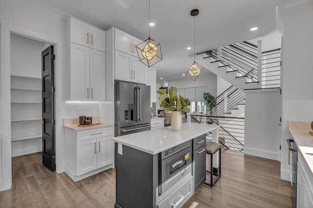 kitchen with a kitchen island, high end fridge, white cabinetry, and light wood-style floors