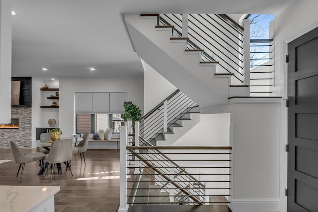 staircase featuring recessed lighting, wood finished floors, and a fireplace