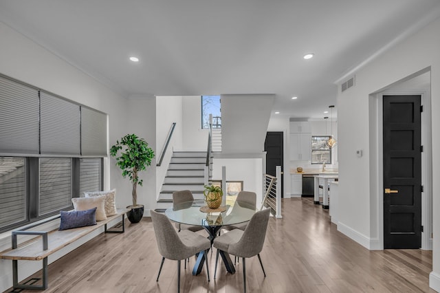 dining room with recessed lighting, light wood-style floors, and stairs