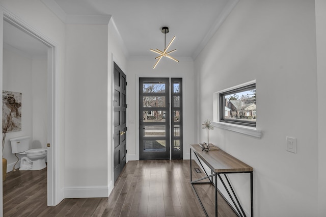 foyer featuring a notable chandelier, dark wood-style flooring, baseboards, and ornamental molding