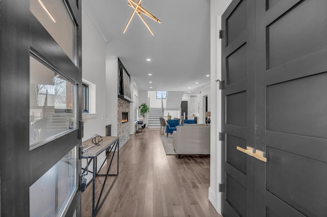 foyer entrance with a stone fireplace, recessed lighting, and wood finished floors