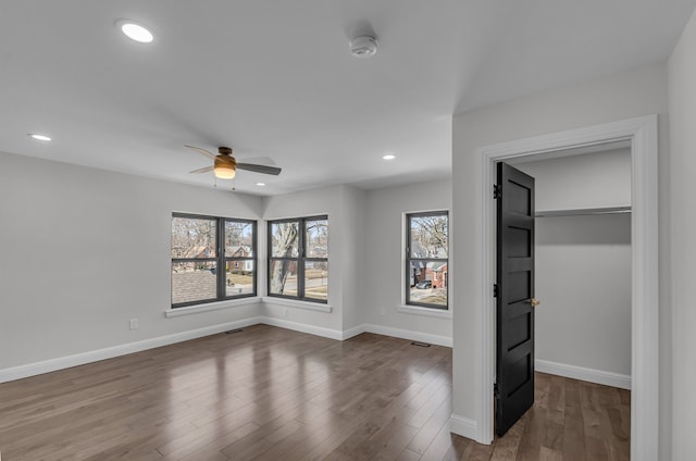 unfurnished bedroom with a spacious closet, visible vents, baseboards, recessed lighting, and dark wood-style flooring